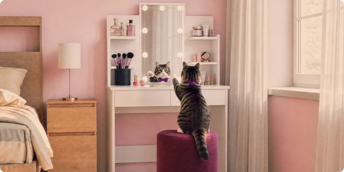Katt som sitter vid ett sminkbord med förvaringshyllor i ett rosa sovrum.