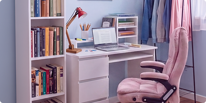 Modern studieplats för studenter med vitt skrivbord, ergonomisk kontorsstol, laptop, bokhylla, förvaringsmöbel och klädställning i ett ljust och organiserat sovrum för bekväma studier och vardagsliv.
