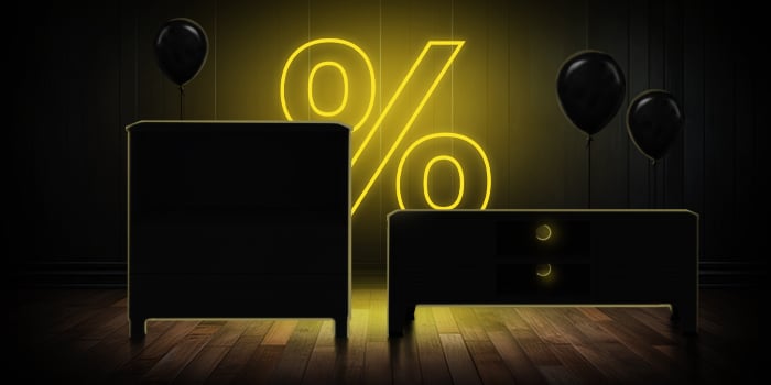 Svart byrå och TV-konsol med svarta ballonger framför en ljust gul procentskylt på ett mörkt trägolv.
